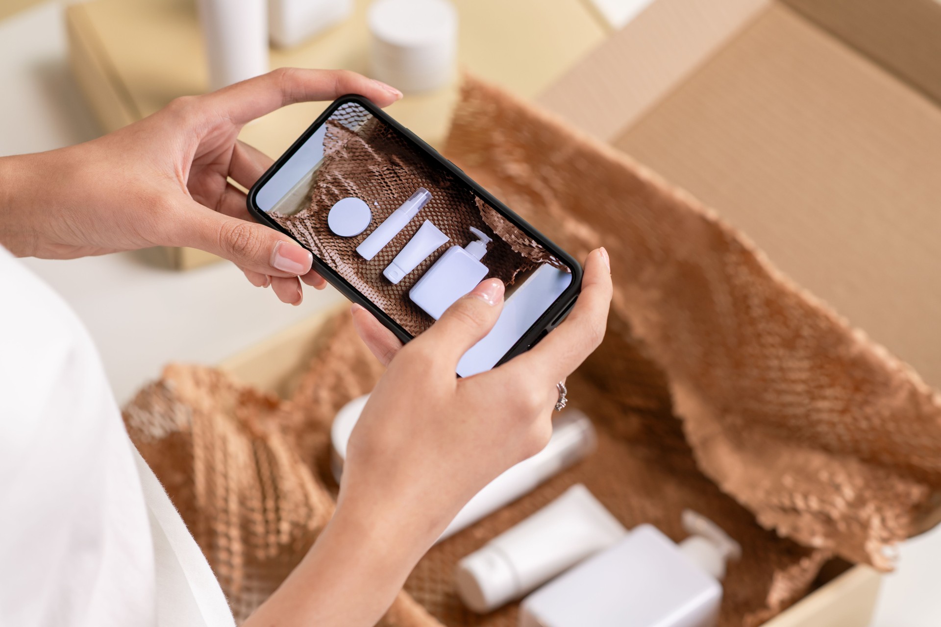 close-up shot of e-commerce seller taking photo of the prepared orders with smartphone in a warehouse setting for an online beauty shop.